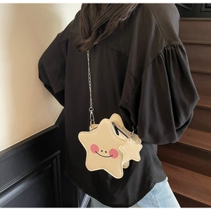 Detailed view of yellow star-shaped crossbody bag with a smiley face and silver chain strap