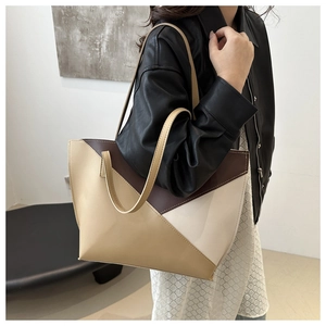 Close-up of geometric color-block tote bag in khaki and coffee leather on model's shoulder