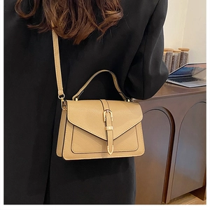 Chic khaki pebbled leather square bag with vertical belt strap shown on a model