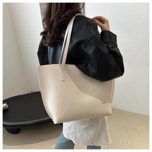 Detail view of a large beige tote bag with geometric stitching on soft faux leather