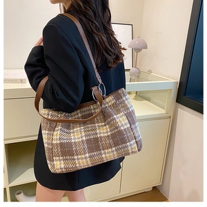 Brown plaid tweed tote bag with leather straps shown on shoulder in a cozy interior