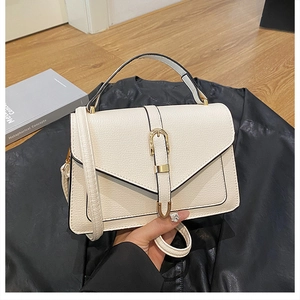 Detailed view of beige lychee leather handbag with V-flap and gold metal buckle