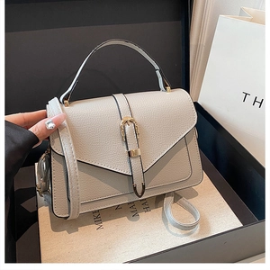 Detail of light grey lychee texture handbag with golden horseshoe buckle on gift box