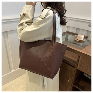Detailed view of dark brown geometric patchwork tote bag shown worn on shoulder