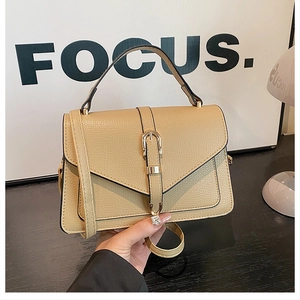 Detail of beige lychee texture leather handbag with gold metal clasp and top handle
