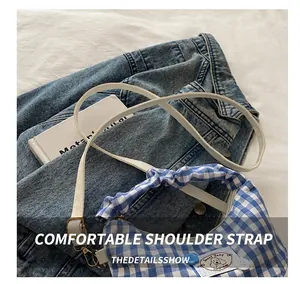 Detail of adjustable white leather strap and blue gingham fabric with floral puppy patch