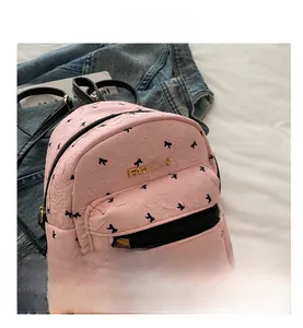 Close-up of pink mini backpack with black bow print and golden FASHION metal logo