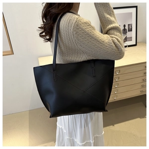 Detail of black tote bag featuring geometric stitching and large capacity on a model