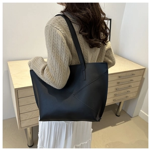 Detail of minimalist black tote bag featuring modern diagonal stitching and matte leather texture