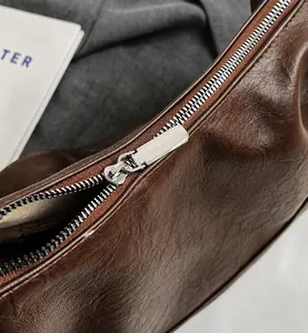 Detail of smooth silver zipper and beige lining on dark brown faux leather tote bag
