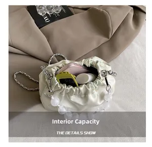 Detail showing the internal capacity of the satin pleated bag with pearls and chain