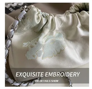 Close-up of premium satin drawstring bag with delicate floral embroidery and chain strap