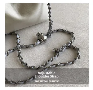 Detail of adjustable shoulder strap with silver chain and sphere clasp on white bag