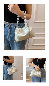 Detail of cream satin pleated bag with floral embroidery and white pearl handle