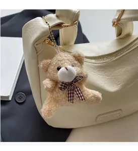 Detail of cream leather dumpling bag with plush bear charm and brand embossing