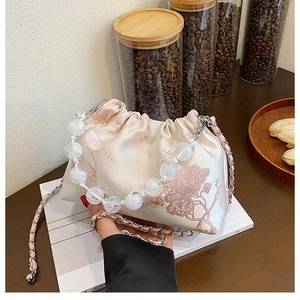 Detail of floral jacquard texture and white acrylic bead chain on small cloud bag