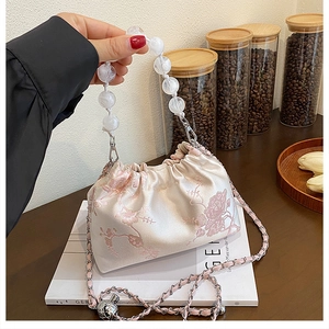 Detail of pink satin floral handbag with marble bead handle and silver chain strap