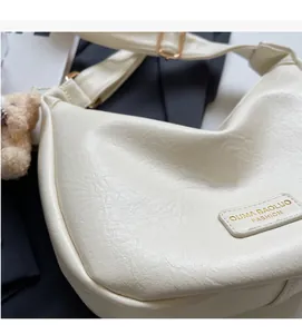 Close-up of cream PU leather hobo bag with lychee texture and a cute plush bear charm