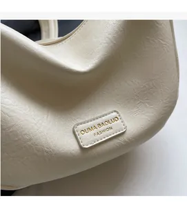 Close-up of off-white lychee grain leather handbag with gold logo and premium texture