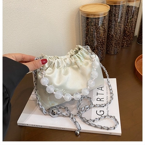 Detailed shot of pale green satin bucket bag with floral jacquard and beaded handle