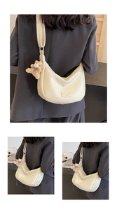 Detail view of cream white crescent bag with lychee texture and plush bear pendant