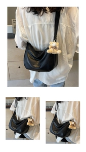 Detail of black crescent shoulder bag with zipper and cute teddy bear plush charm accessory