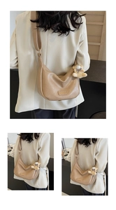 Detail view of khaki crescent shoulder bag with lychee grain texture and bear charm