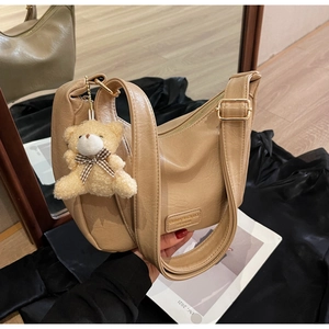 Detail of khaki PU leather crescent bag with metal logo and plush bear charm