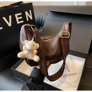 Detail of dark brown dumpling bag in luxury gift box with cute white plush bear charm