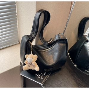 Detail of black faux leather crescent bag with bear charm and bow tie accessory