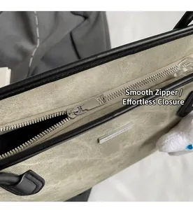 Detailed macro view of smooth silver metal zipper and brand logo plate on stylish tote bag