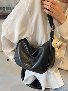 Minimalist black crescent crossbody bag with lychee texture and plush bear pendant