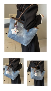 Detail view of large blue-grey marble tote bag with brown straps and plush star charm