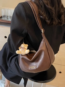Dark brown half-moon hobo bag in lychee textured faux leather with a cute bear charm