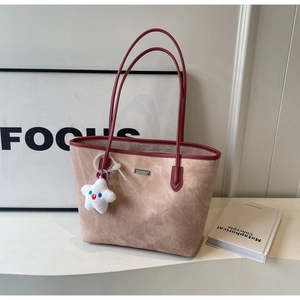 Detail of apricot tote bag with contrast brown handles and cute star plush pendant