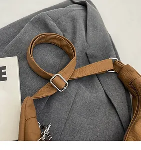 Detail of adjustable brown litchi grain leather shoulder strap with a metal buckle