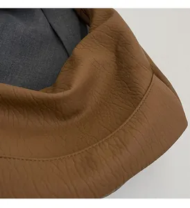 Detail of caramel brown litchi grain leather texture and grey inner lining of the bag