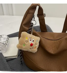 Close-up of brown lychee grain leather crossbody bag with a cute plush charm accessory