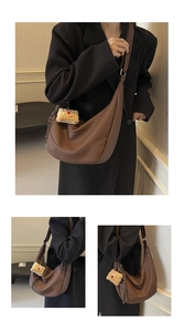 Close-up of brown crescent crossbody bag with lychee texture and plush charm