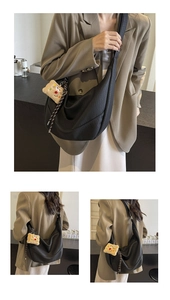 Detail of a black pebbled leather hobo bag with wide strap and plush keychain