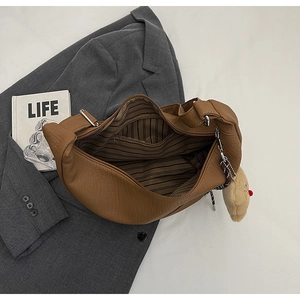 Detail view of brown hobo bag interior with striped lining and plush bear charm