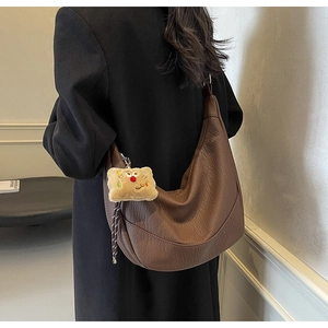 Detail view of large dark brown hobo bag with pebble texture and plush biscuit charm