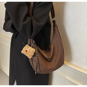 Detail of brown hobo shoulder bag with leather texture and cute yellow plush charm