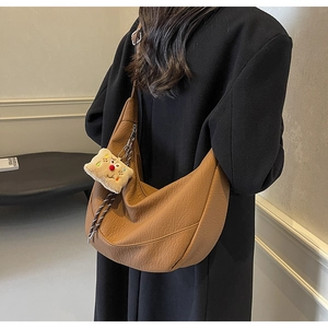 Detail of brown large capacity leather hobo bag with litchi grain and plush charm