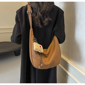 Close-up of brown litchi pattern leather half-moon bag with plush puppy pendant