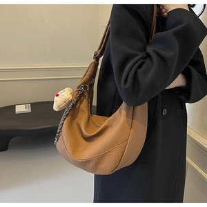 Macro detail of brown leather hobo bag featuring fine texture and cute plush charm