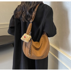 Detail of brown litchi pattern hobo bag featuring a cute plush bread charm on the side