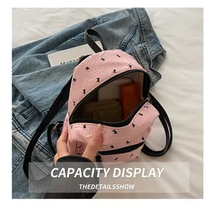 Pink mini nylon backpack with black bow print showing internal storage capacity