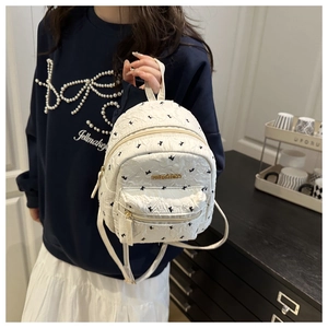 Detail of white pleated mini backpack featuring swallow print and gold FASHION logo
