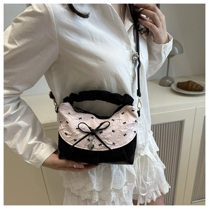 Detailed shot of a pink and black contrast handbag with a bow and heart pendant